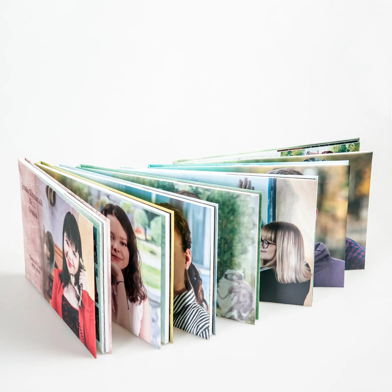 Trei albume de absolvenți cu coperți personalizate, așezate pe o masă